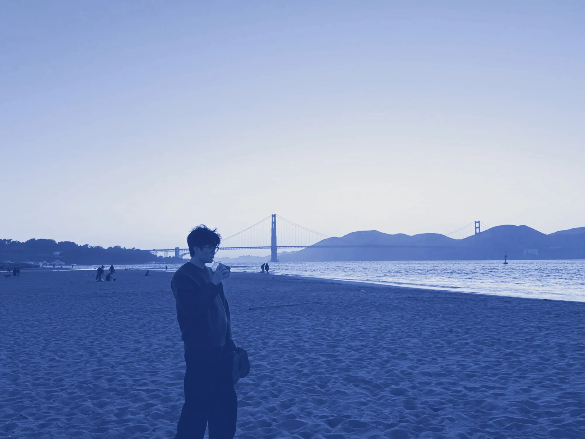 Ian on a beach in San Francisco at sunset, the Golden Gate Bridge behind him, printed in cyanotype blue.